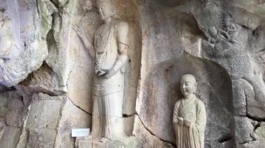 Tarihi bir mağara tapınağının içinde kaya duvarlarına oyulmuş antik Budist heykelleri. Yüzyıllardır süregelen dini sanat ve kültür mirasını yansıtan kutsal mağara heykelleri..