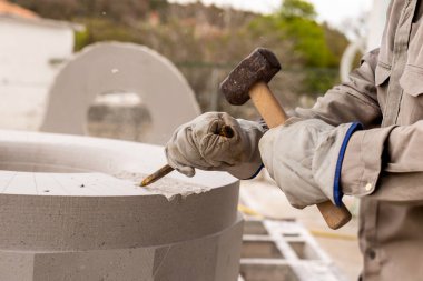 Mavi kazaklı bir kadın ham jambon dilimli tahta bir tahta tutuyor. Onun yanında, ahşap bir masanın üzerinde bir bardak kırmızı şarap var. Kurulum açık havada, arka planda çim var. Bu da bir dağ kulübesi kurulduğunu gösteriyor..