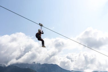 Bir kadın dağ semalarında zeplinle uçarken bulutlar aşırı spor koşum takımı kask yüksekliği adrenalin açık havada macera heyecanı.