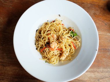 İtalya 'nın Campania bölgesindeki Napoli şehrinin tipik bir makarnası olan sarımsak ve yağlı spagetti, karides ve mürekkep balığıyla birlikte eklendi. Beyaz tabakta servis edilmiş. Üst görünüm.