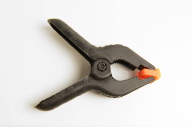 Turuncu uçlu siyah plastik bir yay kıskacının yakın çekimi, sıklıkla fotoğraf için kağıt, fotoğraf ve zemin klemplerinde kullanılır..