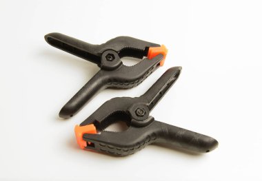 Turuncu uçlu iki siyah plastik yay kıskacının yakın çekimi, sıklıkla fotoğraf için kağıt, fotoğraf ve zemin klemplerinde kullanılır..