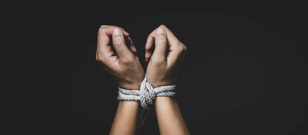 Woman hand tied up with rope, depicting the idea of freedom of the press or freedom of expression on dark background in low key. International human right day concept.