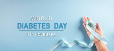 Dünya Diyabet Günü Farkındalık Konsepti. El ele tutuşan mavi kurdele, sembolik yay rengi pastel arka planda diyabet gününde farkındalığı artırıyor, 14 Kasım.