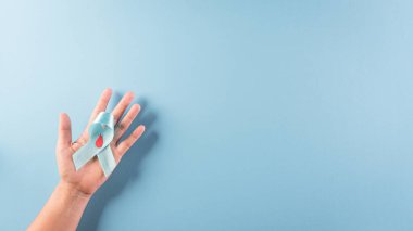 Dünya Diyabet Günü Farkındalık Konsepti. El ele tutuşan mavi kurdele, sembolik yay rengi pastel arka planda diyabet gününde farkındalığı artırıyor, 14 Kasım.