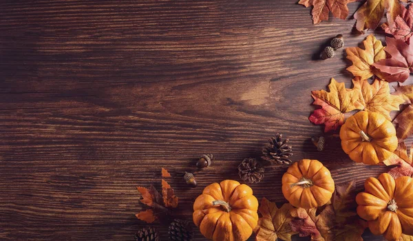 Thanksgiving background decoration from dry leaves and pumpkin on old wooden background. Flat lay, top view with copy space for Autumn, fall, Thanksgiving concept.