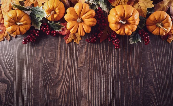 Thanksgiving background decoration from dry leaves and pumpkin on old wooden background. Flat lay, top view with copy space for Autumn, fall, Thanksgiving concept.
