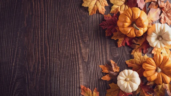 Thanksgiving background decoration from dry leaves and pumpkin on old wooden background. Flat lay, top view for Autumn, fall, Thanksgiving concept.