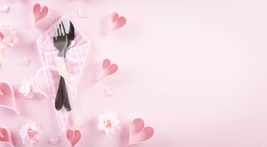 Masa seti, gümüş çatal ve kaşık seti olan pembe kağıt kalpler. Aşk ve Sevgililer Günü konsepti.