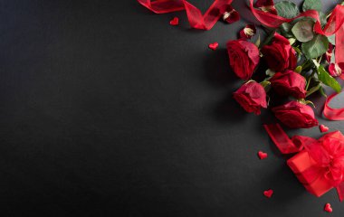 Aşk ve Sevgililer Günü kavramı kırmızı gül ve siyah ahşap arka planda hediye kutusundan yapılmıştır. Kopyalama alanı olan üst görünüm, düz yatay.