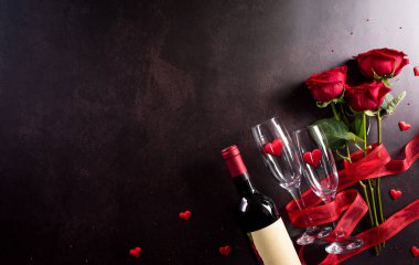 Aşk ve Sevgililer Günü konsepti şampanya kadehleri, şarap, kırmızı kalpler ve koyu taştan bir arka planda gül. Kopyalama alanı olan üst görünüm, düz yatay.