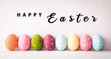 Paskalya dekorasyonun kutlu olsun! Parlak beyaz ahşap arka planda Paskalya yumurtaları.