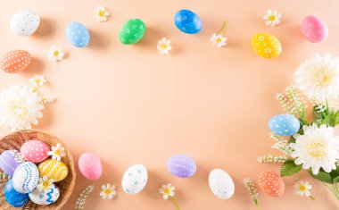 Mutlu Paskalyalar! Renkli paskalya yumurtaları ve pastel arka planda çiçekler. Paskalya Günü için hediyeler ve selamlar zamanı kutluyor. Düz yatış, üst görünüm.