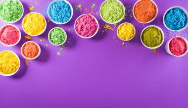 Mutlu Holi Festivali dekorasyonu. Mor arkaplandaki renkli holi tozunun üst görüntüsü. Metin için kopya alanı da var..