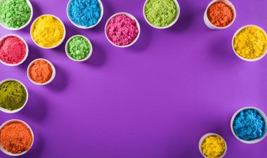 Mutlu Holi Festivali dekorasyonu. Mor arkaplandaki renkli holi tozunun üst görüntüsü. Metin için kopya alanı da var..