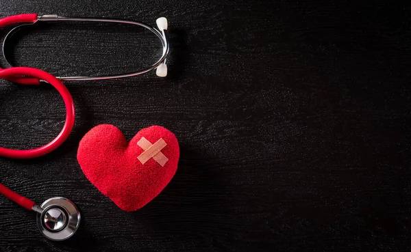 Top view of red heart with doctor physician's stethoscope on dark stone background. Hospital life insurance concept,  World health day concept.