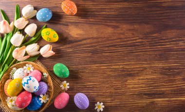 Mutlu Paskalyalar! Koyu ahşap arka planda çiçekli bir sürü Paskalya yumurtası. Paskalya Günü için hediyeler ve selamlar zamanı kutluyor. Düz yatış, üst görünüm.