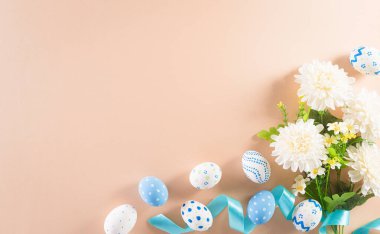Mutlu Paskalyalar! Renkli paskalya yumurtaları ve pastel arka planda çiçekler. Paskalya Günü için hediyeler ve selamlar zamanı kutluyor. Düz yatış, üst görünüm.