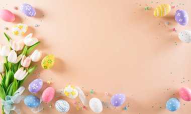 Mutlu Paskalyalar! Renkli paskalya yumurtaları ve pastel arka planda çiçekler. Paskalya Günü için hediyeler ve selamlar zamanı kutluyor. Düz yatış, üst görünüm.