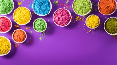 Mutlu Holi Festivali dekorasyonu. Mor arkaplandaki renkli holi tozunun üst görüntüsü. Metin için kopya alanı da var..