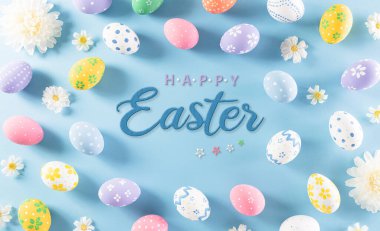 Mutlu Paskalyalar! Pastel mavi arka planda çiçekli Paskalya yumurtaları. Paskalya Günü için hediyeler ve selamlar zamanı kutluyor. Düz yatış, üst görünüm.