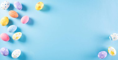 Mutlu Paskalyalar! Pastel mavi arka planda bir sürü Paskalya yumurtası. Paskalya Günü için hediyeler ve selamlar zamanı kutluyor. Düz yatış, üst görünüm.