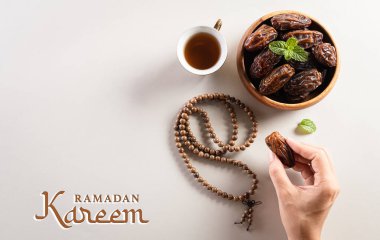 Ramazan Kareem arka plan konsepti, Ellerin toplandığı tarihler meyve, çay ve tespih. Ramazan metniyle düz arkaplan.