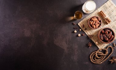 Ramazan Kareem 'in masa üstü resmi, koyu taş zemin üzerinde meyve, süt ve badem tarihleri. Kopyalama alanı olan düz.