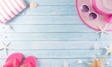 Yaz tatili, seyahat ve tatil konsepti. Güneş gözlüğü, denizyıldızı, plaj şapkası, terlik ve deniz kabuğu pastel mavi ahşap arka planda..