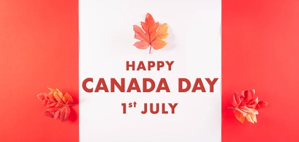 Happy Canada Day concept made from red silk maple leaves with the text on white and red background.