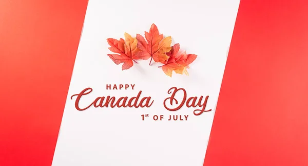 Happy Canada Day concept made from red silk maple leaves with the text on white and red background.