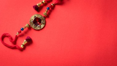 Raksha Bandhan, kızıl arka planda güzel Rakhi ve pirinç taneleri olan Hint festivali. Geleneksel Hint bilekliği kız kardeşler ve erkek kardeşler arasındaki aşkın sembolüdür..