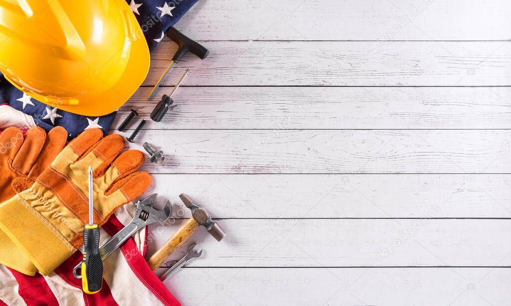 Happy Labor day concept. American flag with different construction tools on white wooden background.