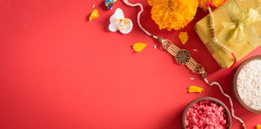Raksha Bandhan, kızıl arka planda güzel Rakhi ve pirinç taneleri olan Hint festivali. Geleneksel Hint bilekliği kız kardeşler ve erkek kardeşler arasındaki aşkın sembolüdür..