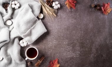 Sonbahar kompozisyonu. Bir fincan kahve, pamuk çiçekleri, sonbahar yaprakları ve koyu taştan arka planda kazak. Düz konum, kopyalama alanı olan üst görünüm.