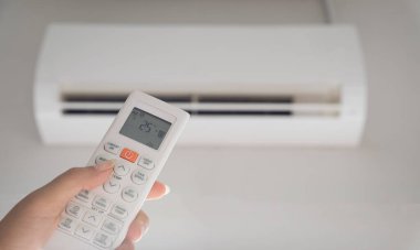 Odanın içindeki klimaya yönlendirilmiş uzaktan kumanda ve ortam sıcaklığına ayarlanmış, 25 santigrat derece..