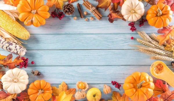 Autumn or Thanksgiving background decoration from dry leaves and pumpkin on  wooden background. Flat lay, top view with copy space.