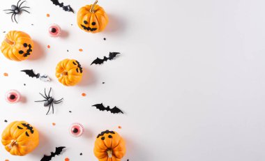 Beyaz arka planda balkabağı, kağıt yarasalar ve siyah örümcekten yapılmış Cadılar Bayramı süslemeleri. Düz konum, metin için kopyalama alanı olan üst görünüm.