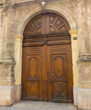 Fransa 'nın Montpellier şehrinde flütlü sütunları ve kemerli bir çevresi olan oyulmuş taş bir kapı içerisindeki barok ahşap bir çift kapı.
