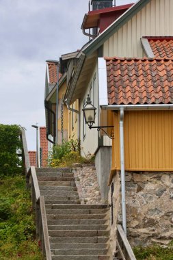 İskandinav eski kasabasında renkli ahşap evler ve merdivenler. Taş merdivenleri ve İskandinav tarzında renkli ahşap evleri olan büyüleyici bir cadde. Tarihi bir mahallede kırmızı kiremitli çatıları ve feneri olan geleneksel İskandinav mimarisi.