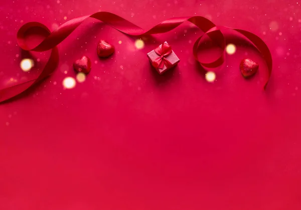 Ярко Красном Фоне Лежит Красный Подарок Луком Атласная Лента Конфеты — стоковое фото