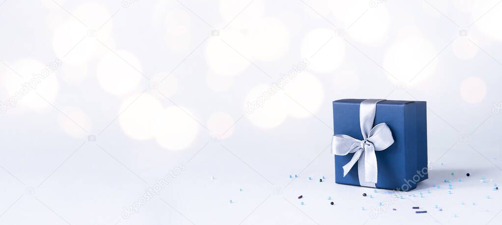 on a white background with a beautiful bokeh there is a blue box with a bow, and pastry confetti are scattered nearb