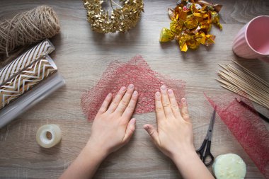 Kendine bir hediye yap. Bir buket şeker, kupada bir kompozisyon. Adım adım talimatlar, adım 7: masanın üzerine, el paketleme ağının kare parçalarının yarısına katlanır.