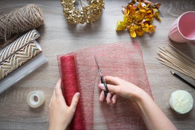 Kendine bir hediye yap. Bir buket şeker, kupada bir kompozisyon. Adım adım talimatlar, beşinci adım: masanın üzerinde, bir el makas ile paketleme ağını keser