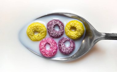 Sütlü bir kaşıkta farklı renklerde 5 mısır gevreği halkası vardır. Konumu Olimpiyat yüzüklerini hatırlatıyor. Olimpiyat sembolü