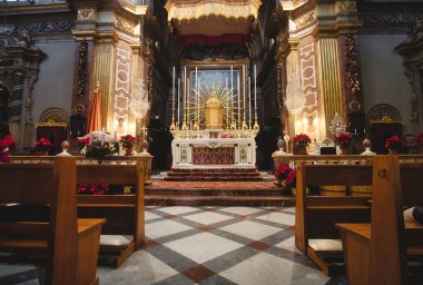 Front view of an altar in a large catholic church with wooden benches or pews