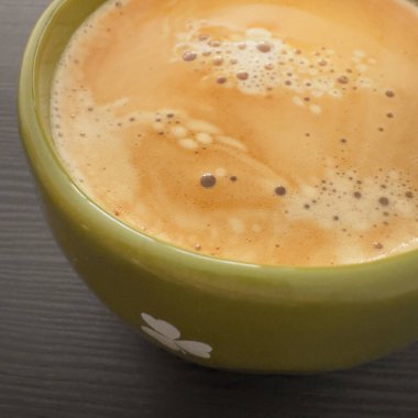 Yeşil seramik bardakta espresso kahvesi koyu masa yüzeyinde kısmen görülebilir. Negatif alanlı en az kahve bileşimi.