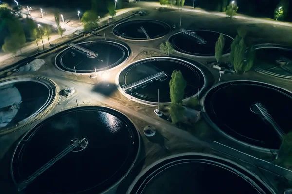 Wastewater Treatment Plant with tanks for purification and filtration of urban waste water, aerial view at night