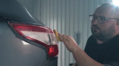 İşçi el ile arka lambaya cilalama macunu uyguluyor ve tüm farları elle cilalıyor. Araba temizleme kavramı