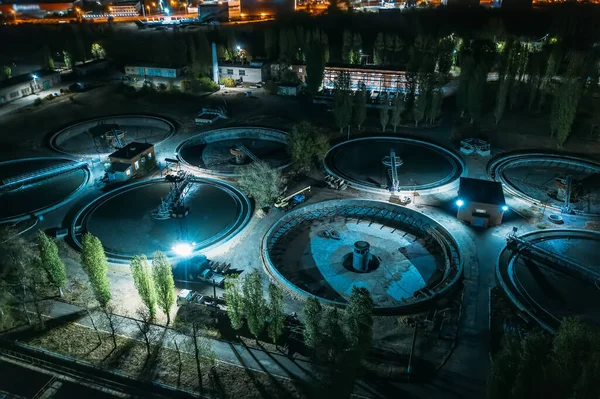 Wastewater Treatment Plant with tanks for purification and filtration of urban waste water, aerial view at night